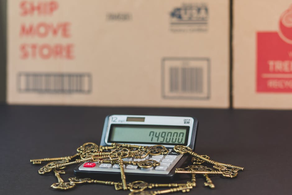 Close-up of a small electronic calculator displaying the number 749800, surrounded by multiple antique brass keys of various shapes and sizes, all resting on a dark surface. In the background, there a