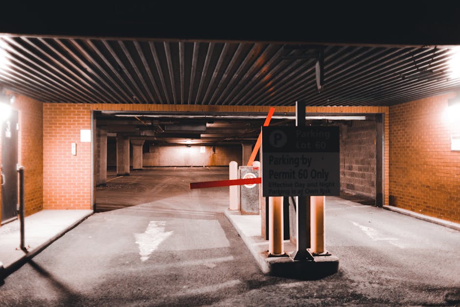 A close-up image of a rectangular 'No Parking Any Time' sign with red text and arrows pointing left and right, mounted on a dark, weathered wooden fence with vertical planks. The surface of the fence shows visible grain and texture, with some small nails or rivets along the bottom edge. The sign is situated in an outdoor environment, likely at the entrance or boundary of a property, indicating parking restrictions. This setting relates to house removals and moving logistics, where adherence to parking restrictions is essential for a smooth loading process, as managed by Man with Van Wood Green. The lighting is natural, highlighting the contrast between the white sign and dark background, emphasizing the importance of parking regulations during home relocation or furniture transport activities.